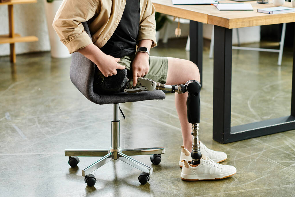 Un bell'uomo d'affari con una gamba protesica seduta su una sedia in ufficio. - Foto, immagini