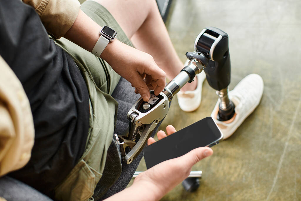 Un hombre de negocios con una pierna protésica sentado y revisando su teléfono celular. - Foto, imagen