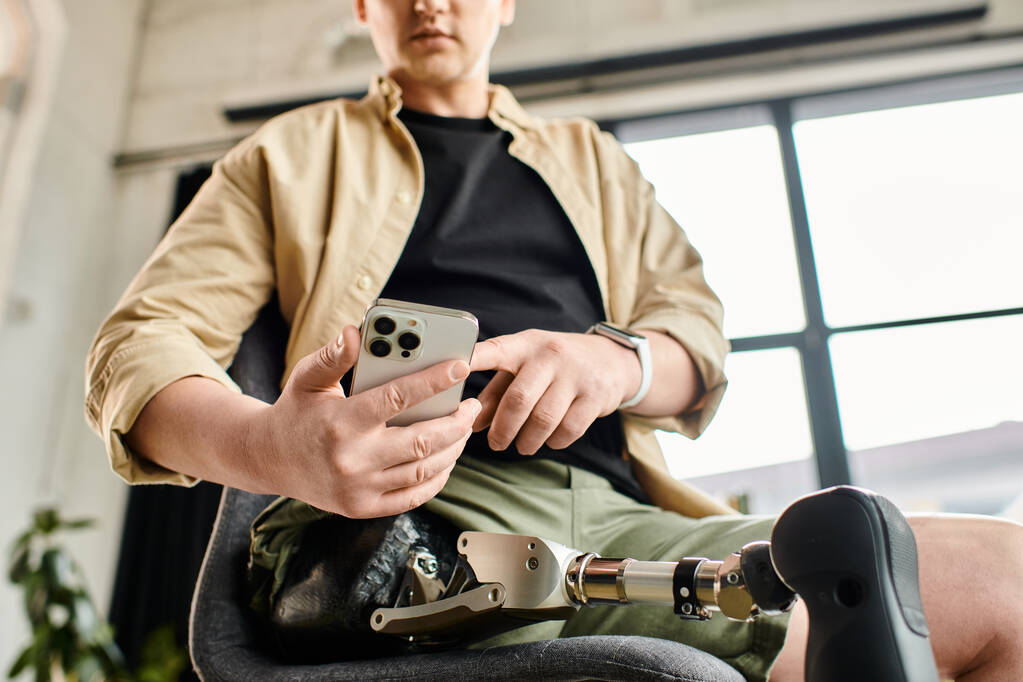 Красивый бизнесмен с протезной ногой, сидящий в кресле, сосредоточенный на своем мобильном телефоне. - Фото, изображение