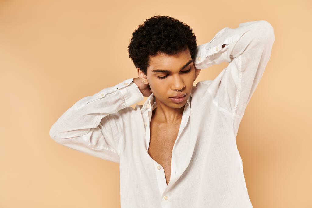 atraktivní elegantní africký Američan muž v elegantním bílém oblečení odvrací pohled na béžové pozadí - Fotografie, Obrázek