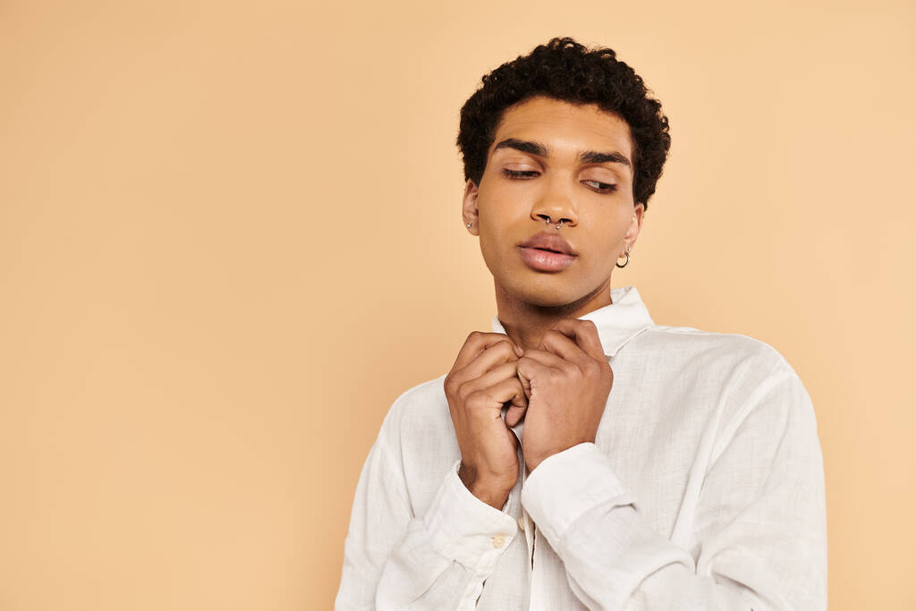 atractivo hombre afroamericano elegante en ropa blanca elegante mirando hacia otro lado en fondo beige - Foto, imagen