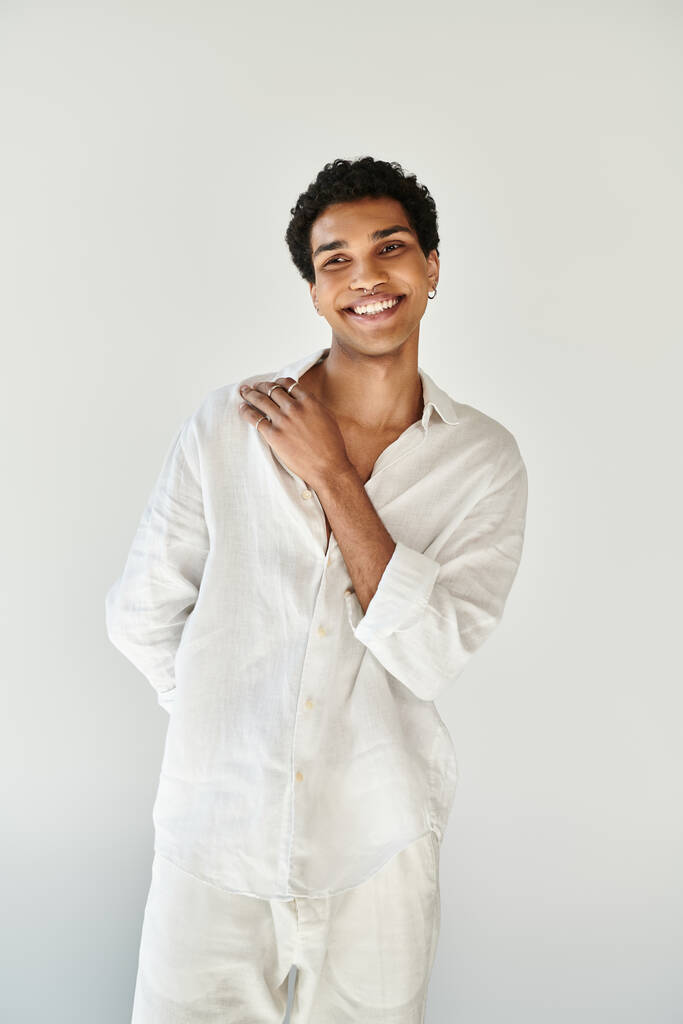 zufrieden verführerisch afrikanisch-amerikanisches Männermodel in weißer Leinenkleidung, das vor beigem Hintergrund wegschaut - Foto, Bild