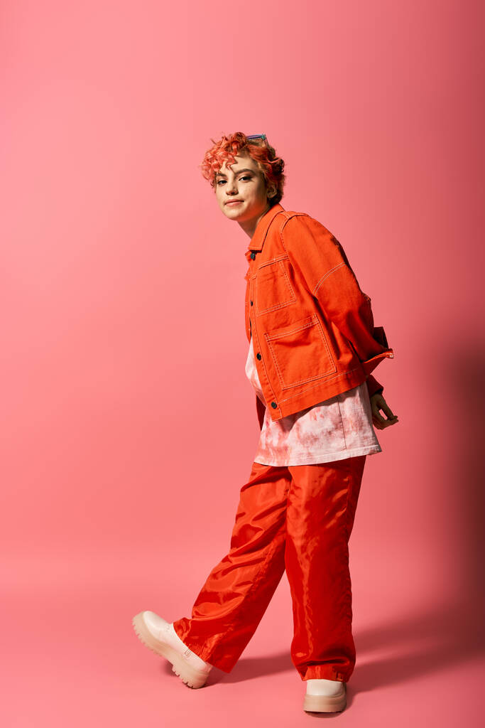 Extraordinary woman dressed in an orange jacket and red pants stands out against a vibrant background. - Photo, Image