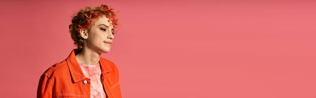 Жінка в помаранчевій куртці впевнено виділяється на яскравому рожевому фоні. - Фото, зображення