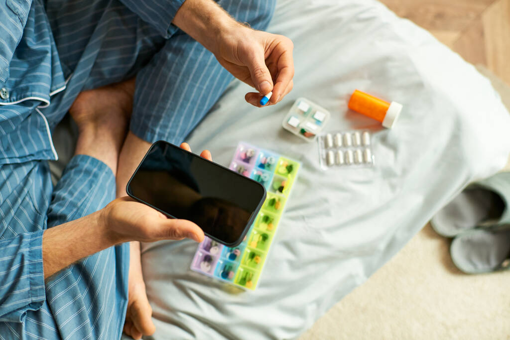 Egy férfi kezében egy okos telefon és tabletta az ágyban reggel. - Fotó, kép