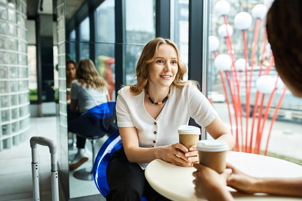 Een vrouw met een diverse achtergrond zit rustig aan een tafel, genietend van een kopje koffie. - Foto, afbeelding