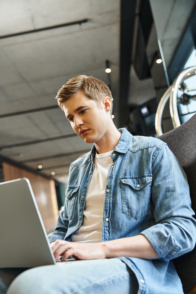 Egy férfi egy székben laptoppal, elmerülve a munkában. Modern üzleti életmód egy coworking térben. - Fotó, kép
