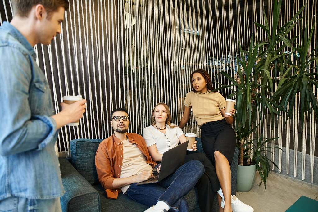 Eine bunte Gruppe von Kollegen sitzt auf einer Couch in einem modernen Raum und diskutiert lebhaft über ihr Startup-Projekt. - Foto, Bild