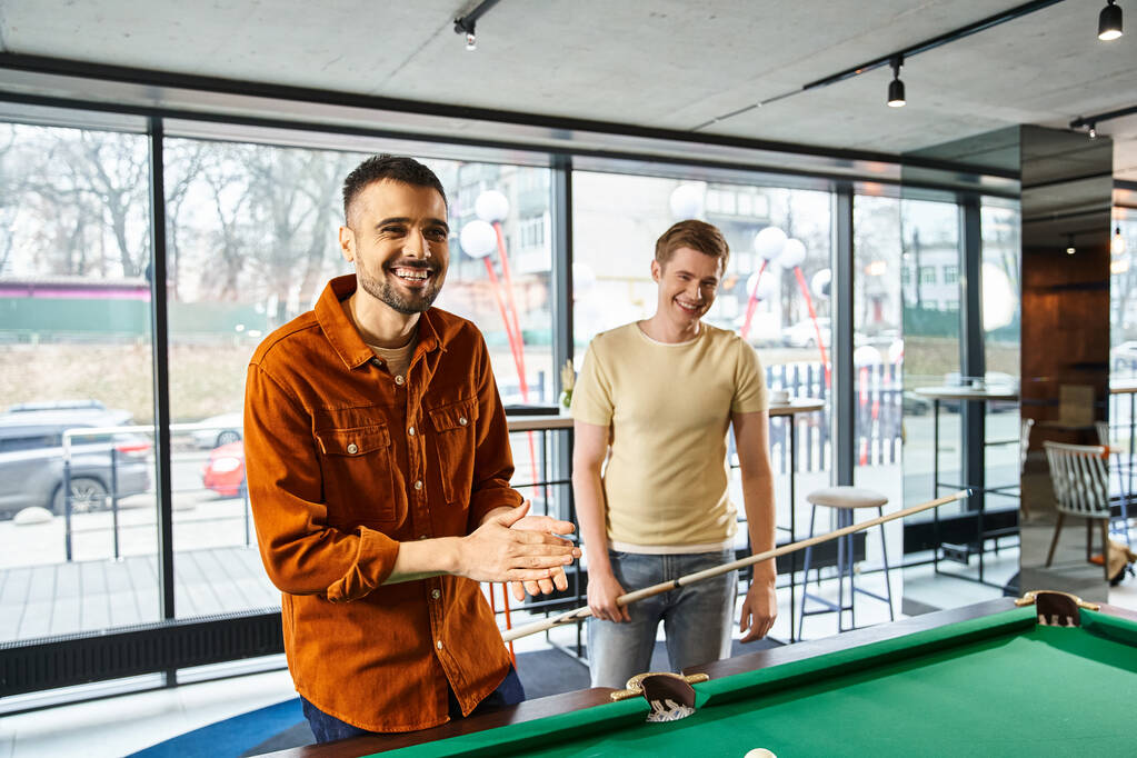 Due uomini che strategizzano e giocano a biliardo in uno spazio di coworking, riflettendo un moderno stile di vita aziendale con un'atmosfera da team di startup. - Foto, immagini