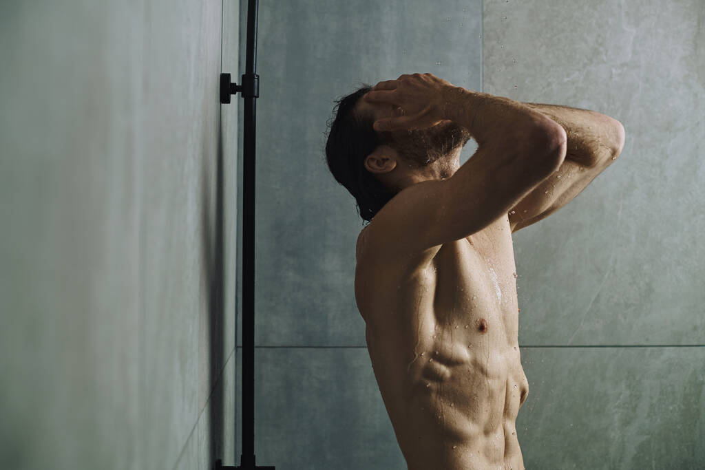 Мужчина без рубашки принимает душ и готовится к дню. - Фото, изображение