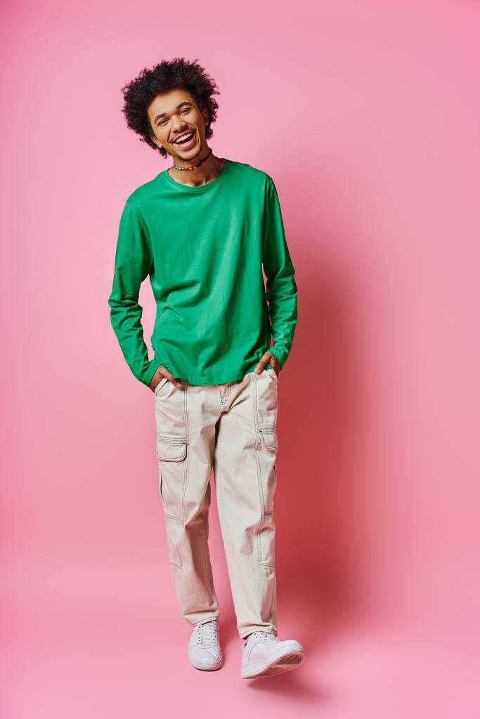 Un jeune homme afro-américain joyeux et frisé se tient en tenue décontractée, affichant une gamme d'émotions sur un fond rose. - Photo, image