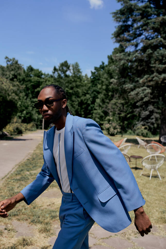 Stílusos afro-amerikai férfi kék öltönyben magabiztosan sétál a járdán.. - Fotó, kép