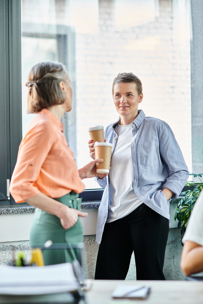 Twee divers zakenvrouwen die samen koffie drinken in een co-working ruimte. - Foto, afbeelding