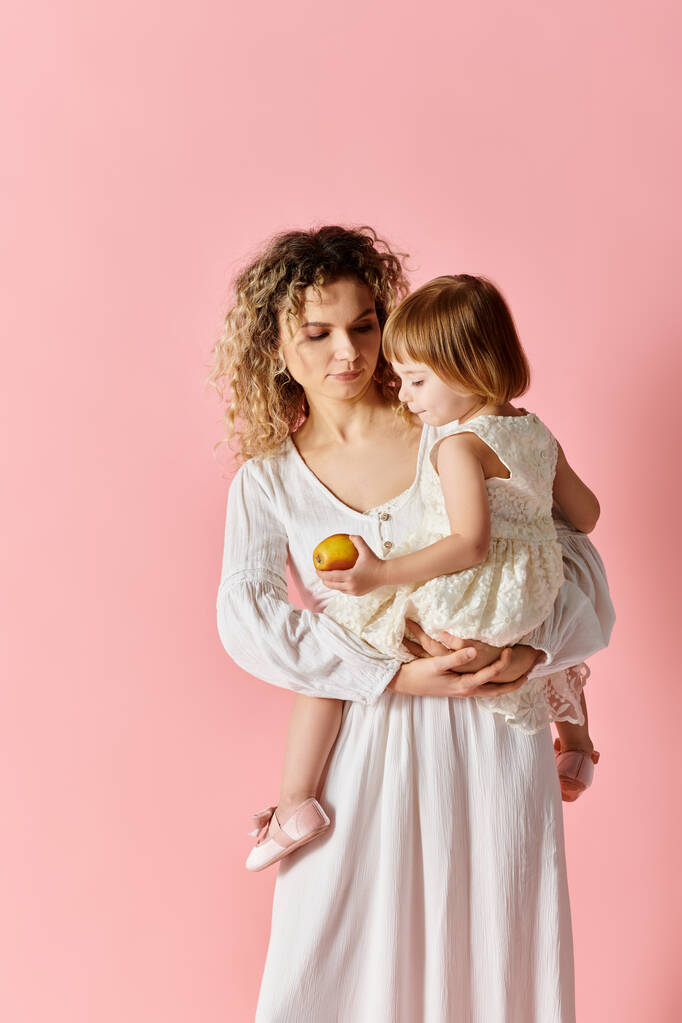 vrouw houden kind in witte jurk op roze achtergrond. - Foto, afbeelding