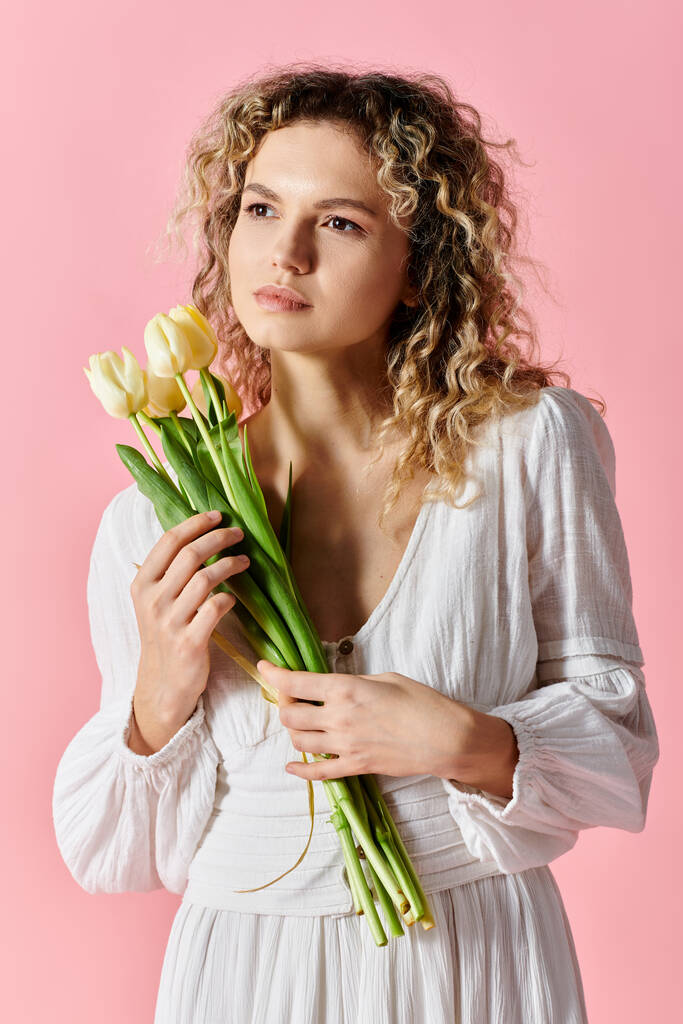 Schöne Frau hält Tulpenstrauß auf rosa Hintergrund. - Foto, Bild