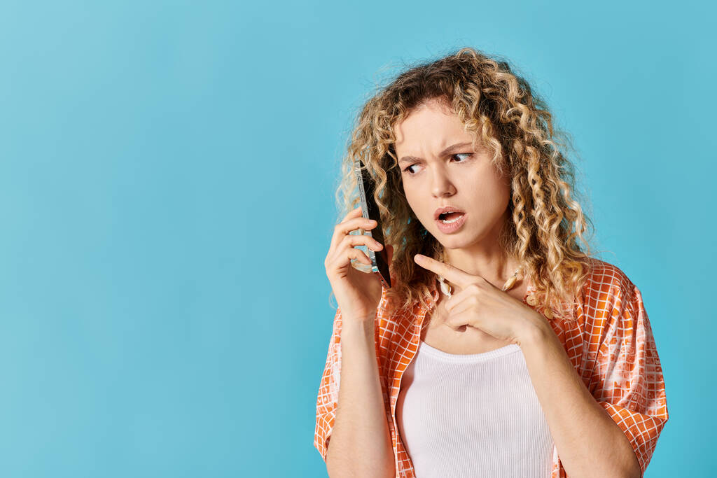 Uma jovem mulher com cabelo encaracolado falando em um telefone celular. - Foto, Imagem