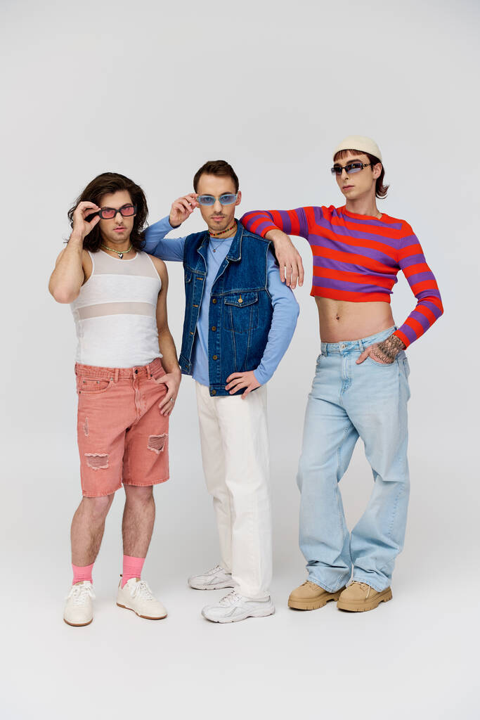 drie stijlvolle aantrekkelijke gay vrienden in levendige trendy kleding met chique zonnebril, trots maand - Foto, afbeelding