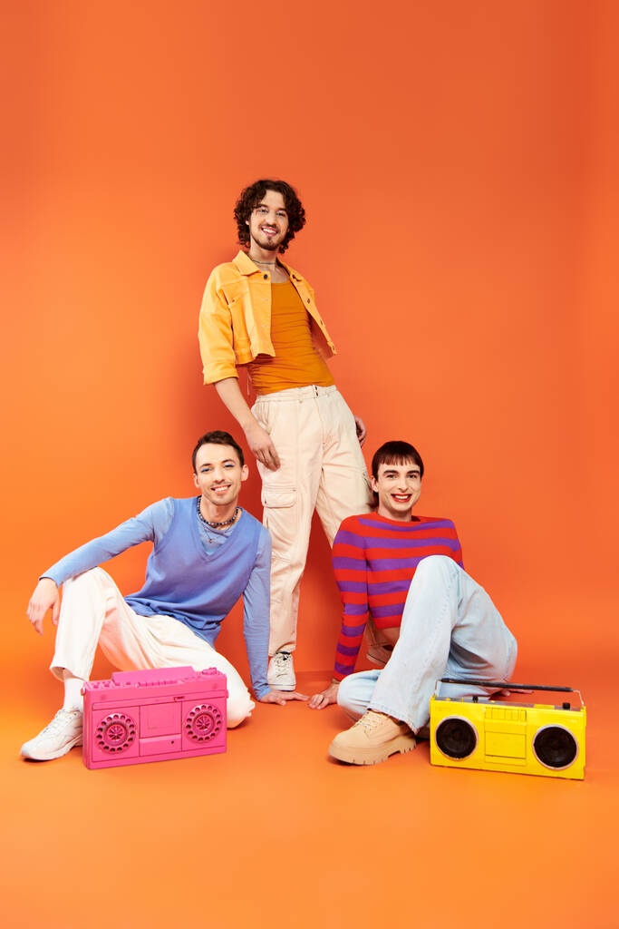 three jolly attractive gay friends in vivid attire posing with tape recorders, pride month - Photo, Image