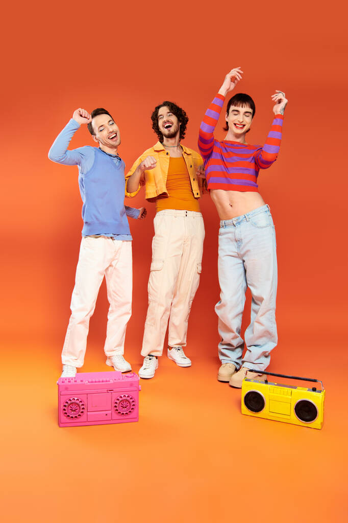 テープレコーダーとポーズする鮮やかな服装で3人の楽しい魅力的なゲイの友人,プライド月 - 写真・画像