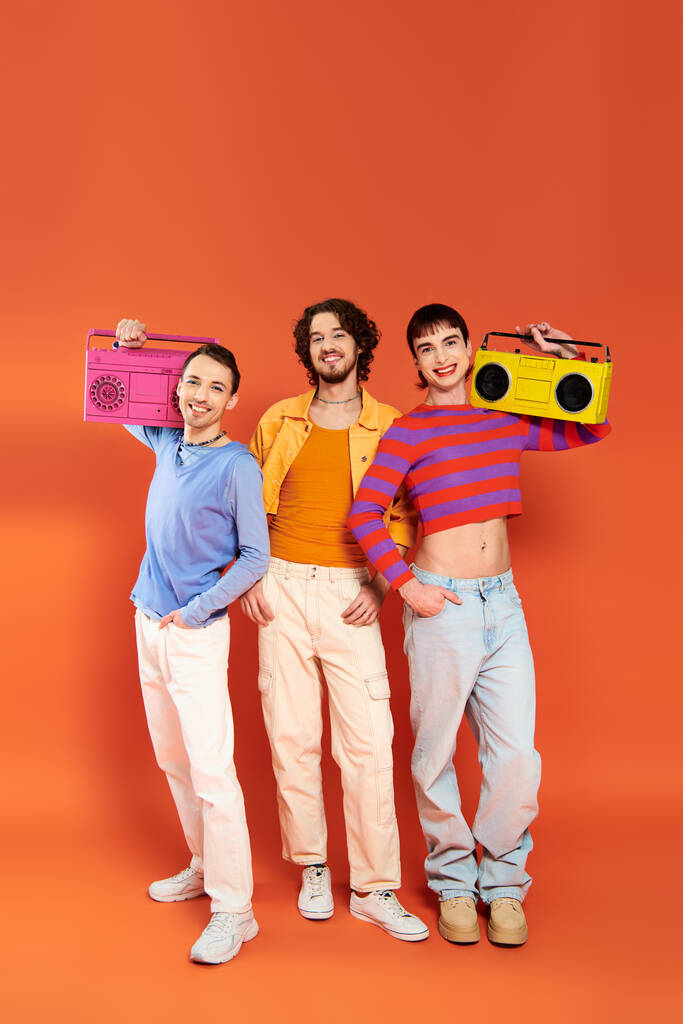three cheerful appealing gay friends in vivid attire posing with tape recorders, pride month - Photo, Image