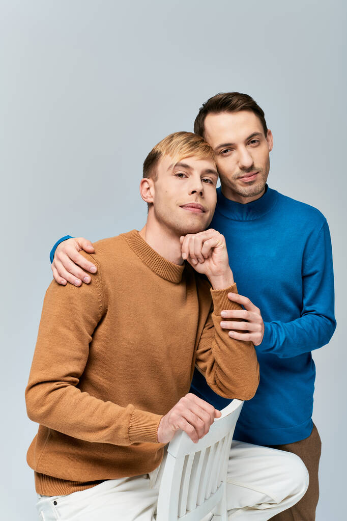 Um casal gay amoroso em traje casual posando juntos em um pano de fundo cinza. - Foto, Imagem