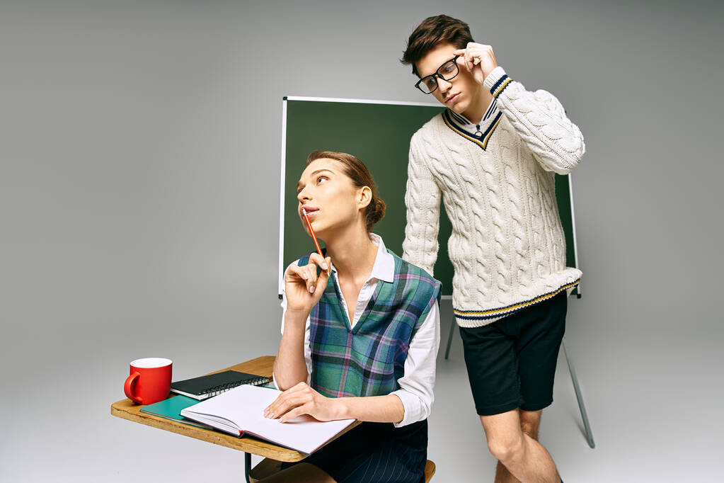 Ein Mann und eine Frau stehen elegant vor einem grünen Brett und posieren für ein College-Setting. - Foto, Bild