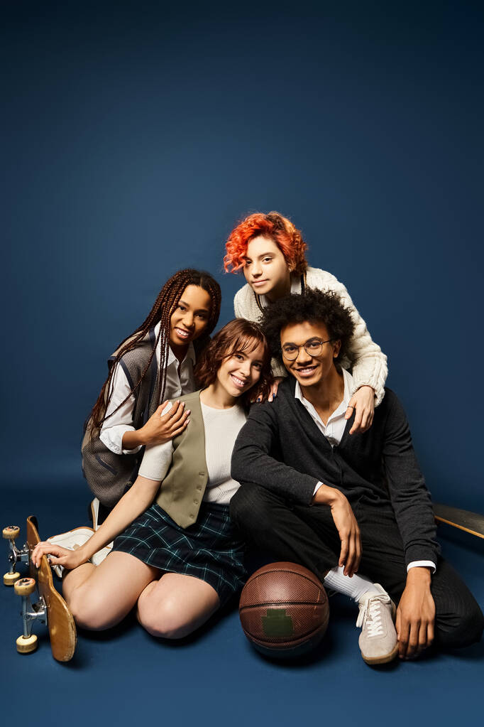 Multikulturelle Gruppe junger Freunde, die in stilvoller Kleidung vor dunkelblauem Hintergrund zusammensitzen. - Foto, Bild