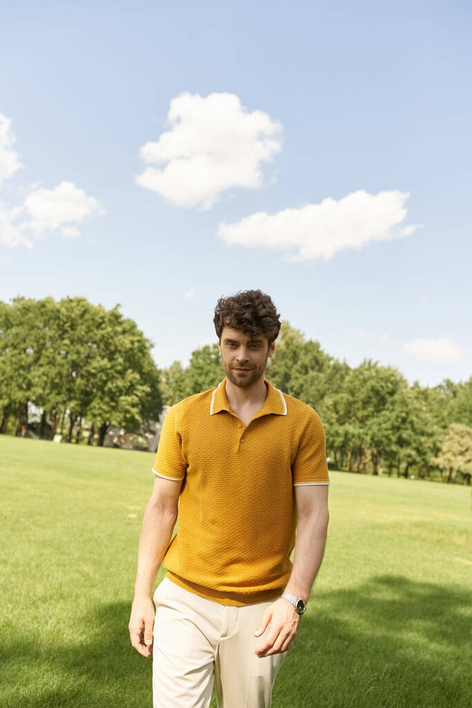 Muž ve žluté polo košili elegantně kráčí pulzujícím polem. - Fotografie, Obrázek