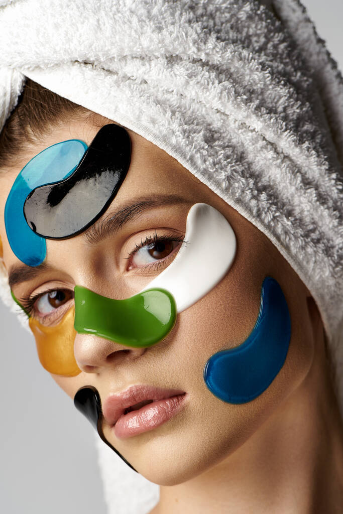 Een mooie jonge vrouw, het dragen van ooglapjes en make-up, poseert sierlijk met een handdoek om haar hoofd. - Foto, afbeelding