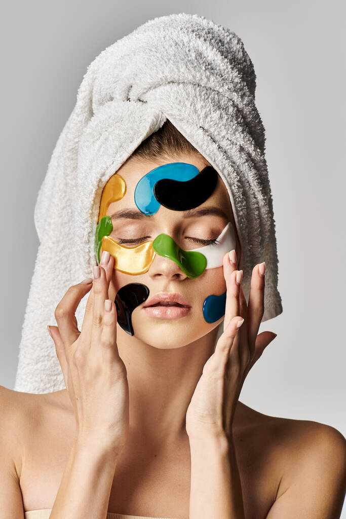 Una giovane donna serena ed elegante con macchie sugli occhi sul viso, in mostra una routine di bellezza con asciugamani avvolti intorno alla testa. - Foto, immagini