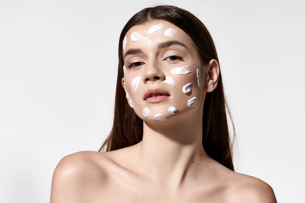 Une jeune femme respire la sérénité avec de la crème blanche sur le visage, mettant en valeur un maquillage unique et artistique. - Photo, image