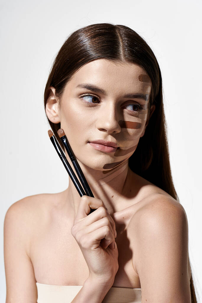 Een vrouw met make-up op haar gezicht, met een borstel voor cosmetische toepassing. - Foto, afbeelding