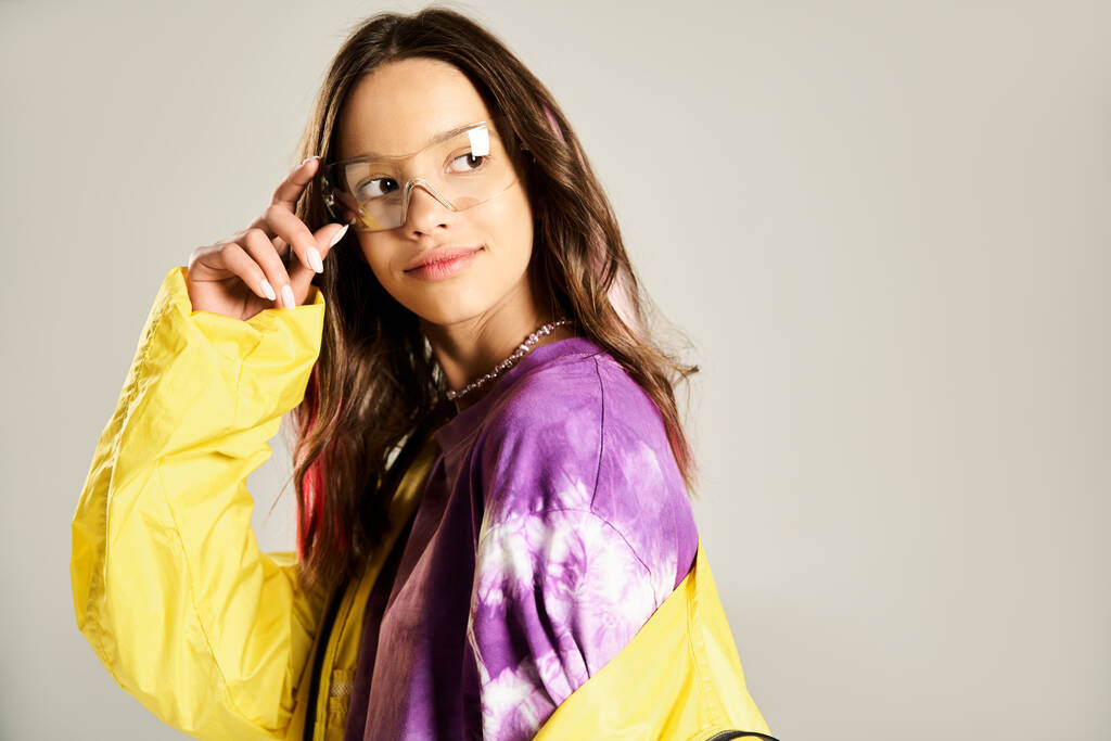 Tyylikäs teini-ikäinen tyttö keltaisessa ja violetissa paidassa puhuu aktiivisesti matkapuhelimella. - Valokuva, kuva