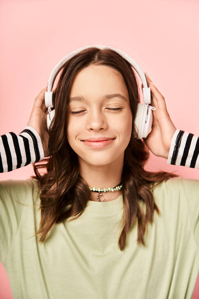 Stylowa nastolatka w żywym stroju nosi słuchawki, ciesząc się muzyką. - Zdjęcie, obraz