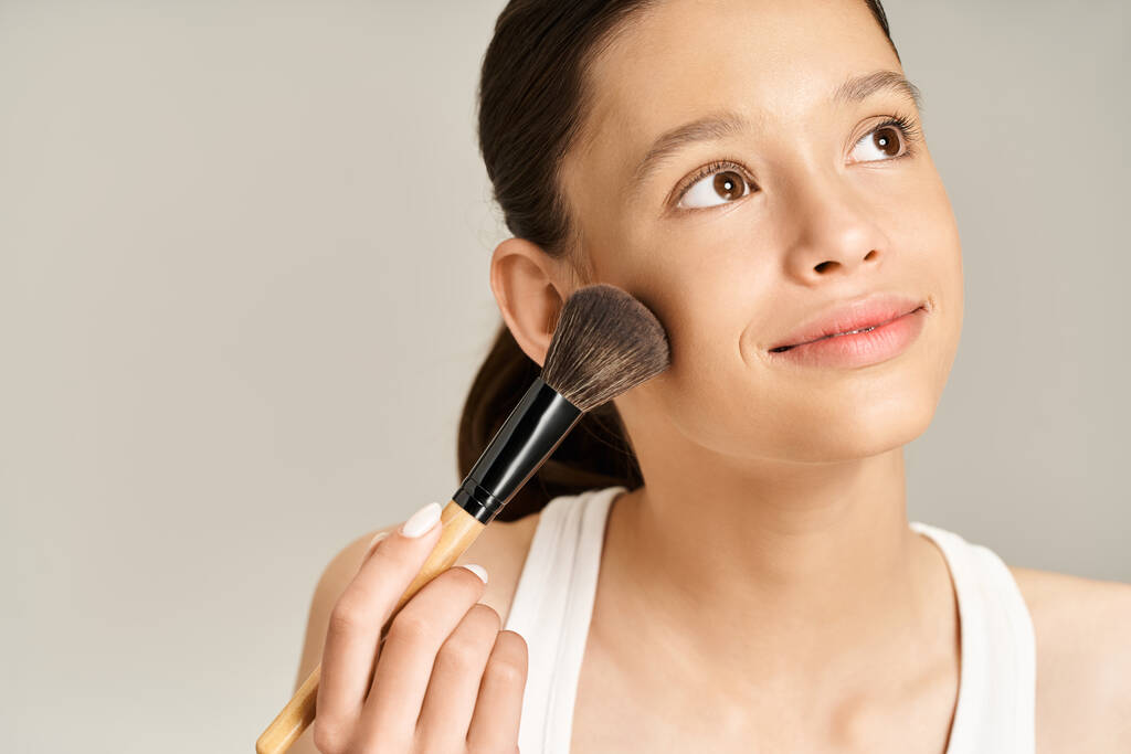 Una adolescente con estilo en traje vibrante apasionadamente sostiene un cepillo de maquillaje. - Foto, imagen