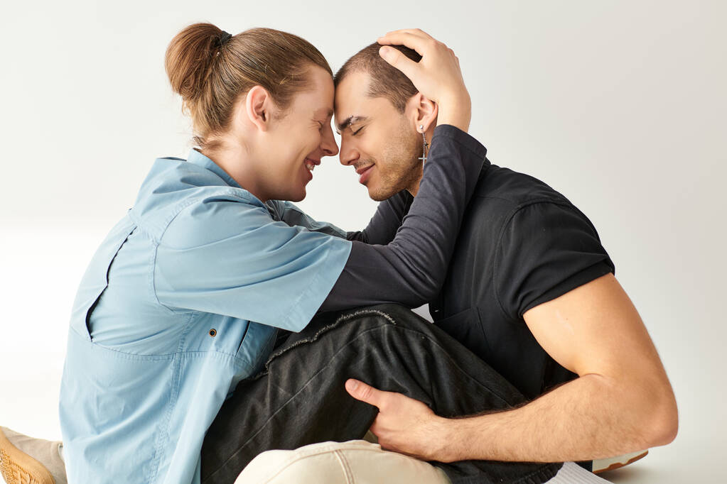 Ένα γκέι ζευγάρι κάθεται κοντά στο πάτωμα, εκφράζοντας αγάπη και οικειότητα. - Φωτογραφία, εικόνα