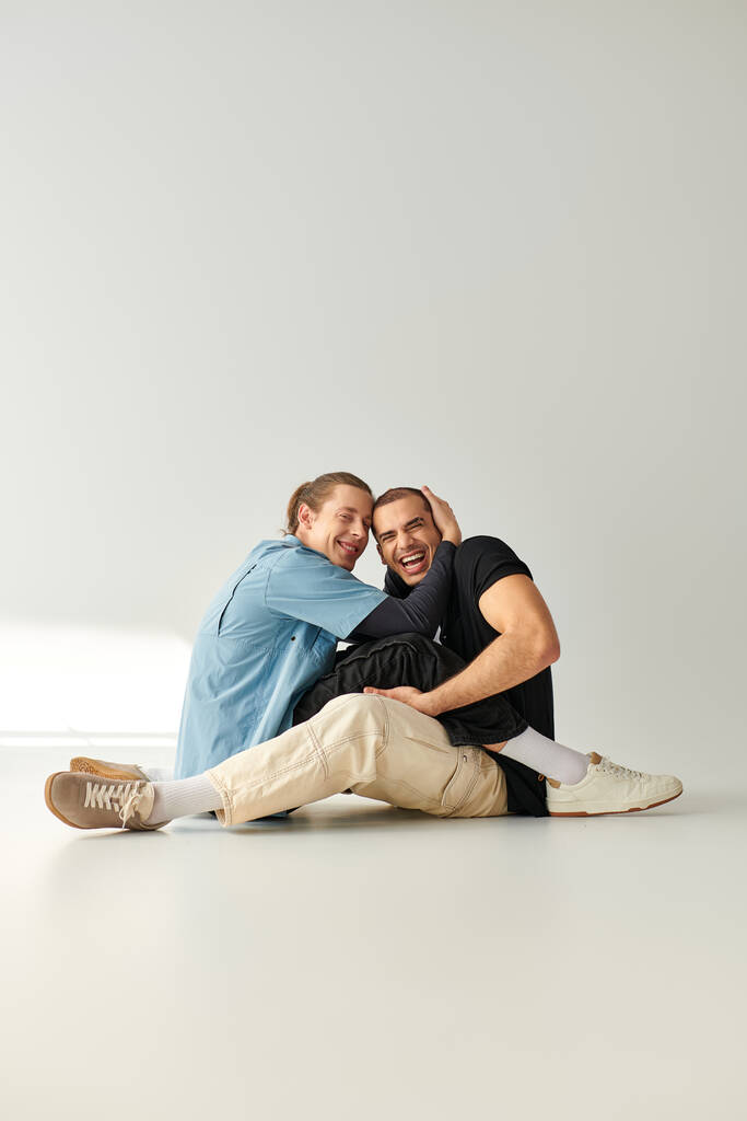 Kaksi miestä, viehättävä ja rakastava homopari, istuu kauniisti valkoisella lattialla.. - Valokuva, kuva