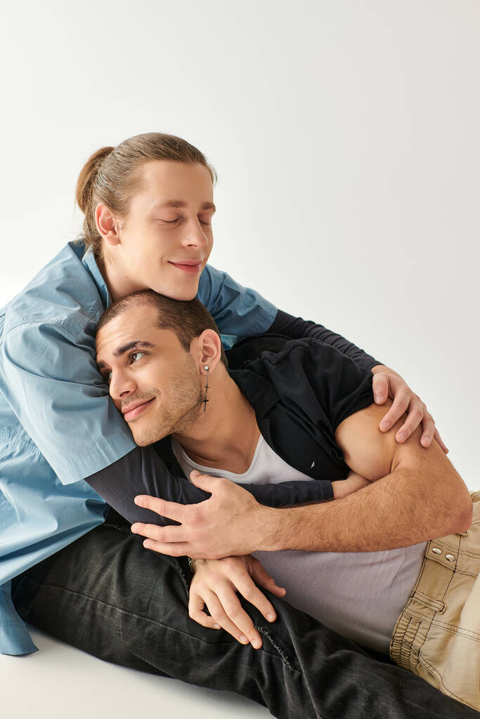 Twee mannen, een liefdevol homostel, zittend op de grond, een vredig moment delend. - Foto, afbeelding