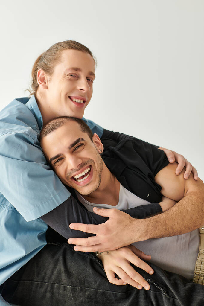 Zwei Männer zeigen Zuneigung, indem sie eng auf einer Couch sitzen und sich liebevoll umarmen. - Foto, Bild