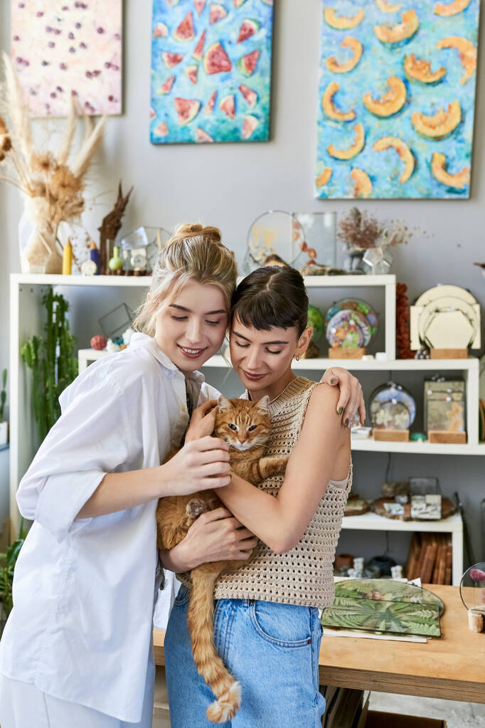 Két nő ölelget egy macskát egy kényelmes szobában.. - Fotó, kép
