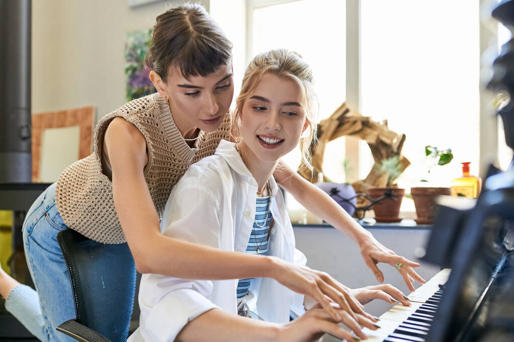 Лесбийская пара страстно играет на фортепиано в художественной студии. - Фото, изображение