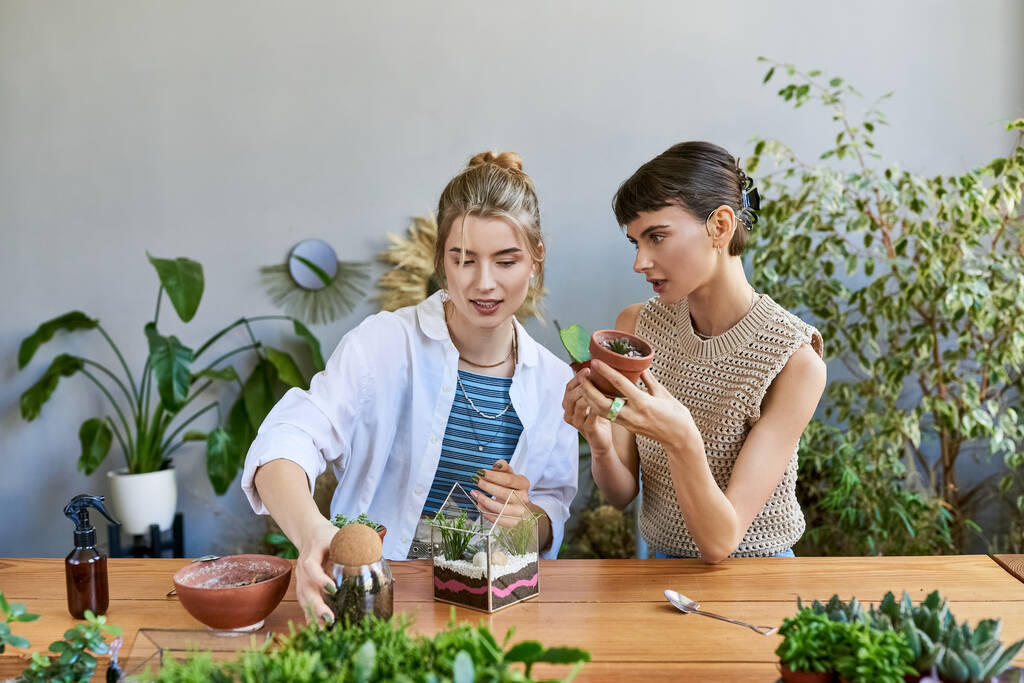 Twee vrouwen geabsorbeerd in tuinieren aan een tafel in een atelier. - Foto, afbeelding