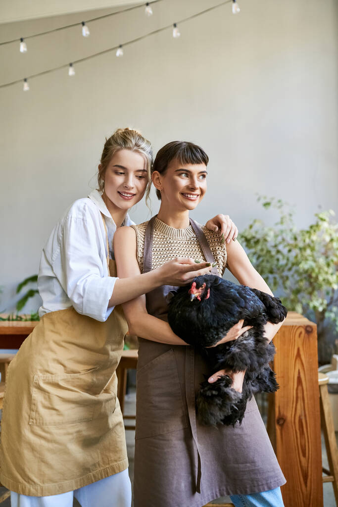Zwei Frauen halten in einem Kunstatelier zärtlich ein Huhn in der Hand. - Foto, Bild