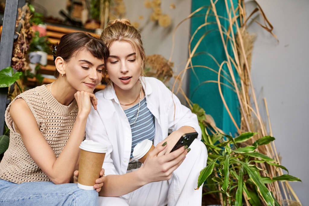 Zarte lesbische Paar teilen einen Moment, vertieft in Handy. - Foto, Bild