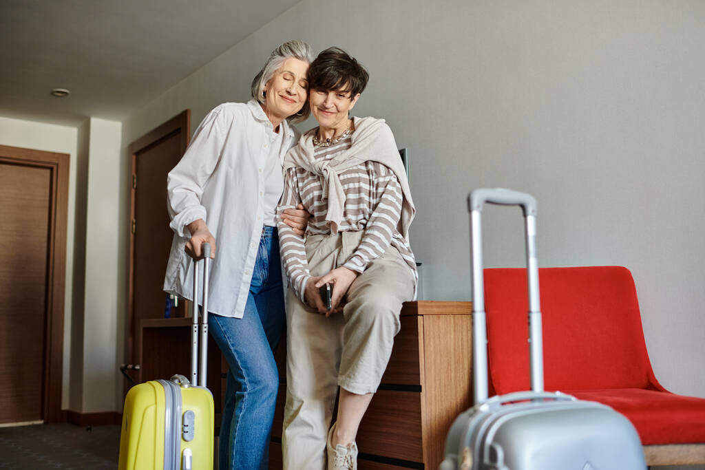 Dos mujeres lesbianas mayores con el equipaje de pie juntos. - Foto, imagen