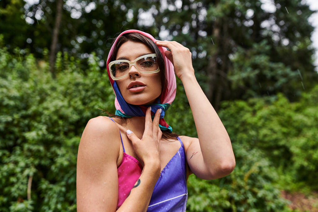 Une jeune femme, vêtue vibramment, profite d'une brise estivale avec une écharpe autour de la tête. - Photo, image