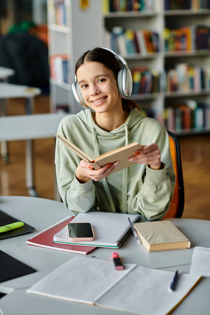 Egy tinédzser lány lefoglal egy könyvet fejhallgatóval, elmerül a békés magányban egy könyvtárban.. - Fotó, kép