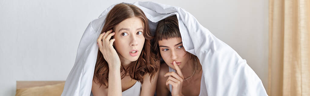 Zwei Frauen suchen Zuflucht unter einer kuscheligen Decke. - Foto, Bild