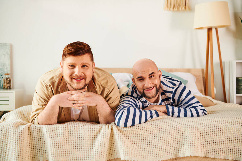 A gay couple enjoying a peaceful moment while laying on a bed. - Фото, изображение