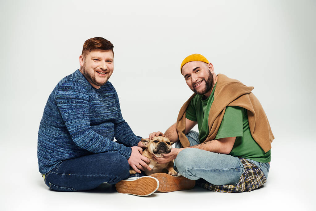 Rakastava homopari istuu yhdessä rakkaan ranskalaisen bulldogin kanssa.. - Valokuva, kuva